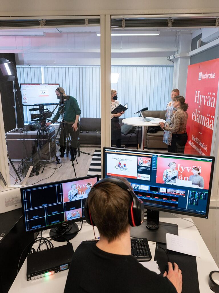 Hoivatien striimaustuotannon ohjausnäkymä, jossa asiantuntija seuraa monitoreista studiossa kuvattavaa lähetystä osana Luma Creativen case-esittelyä.