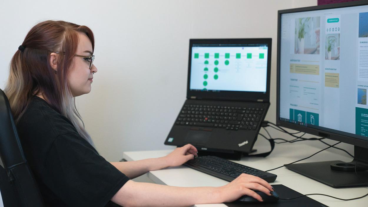 Luma Creativen blogiartikkelin tilannekuva, jossa harjoittelija työskentelee toimistopisteellä. Kuva visualisoi medianomiopiskelijan käytännön työtehtäviä, kuten visuaalista suunnittelua ja digitaalisten sisältöjen työstämistä osana mainostoimiston tiimiä.
