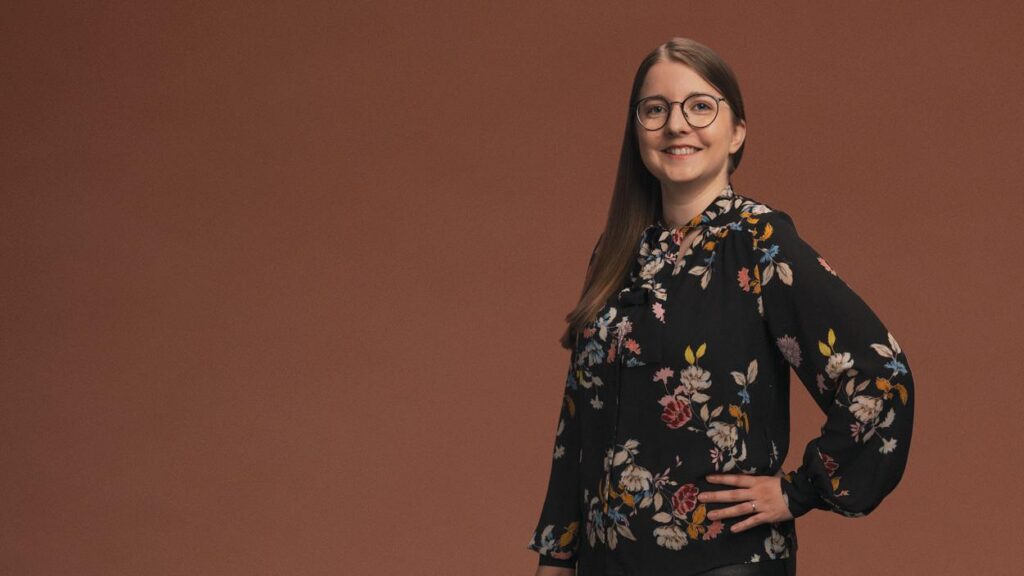 Luma Creativen asiantuntijakuva, jossa hymyilevä nainen poseeraa ruskeaa taustaa vasten. Kuva edustaa asiantuntijuutta ja henkilökohtaista otetta Google Analytics 4 -analytiikkauudistusta käsittelevässä blogiartikkelissa.