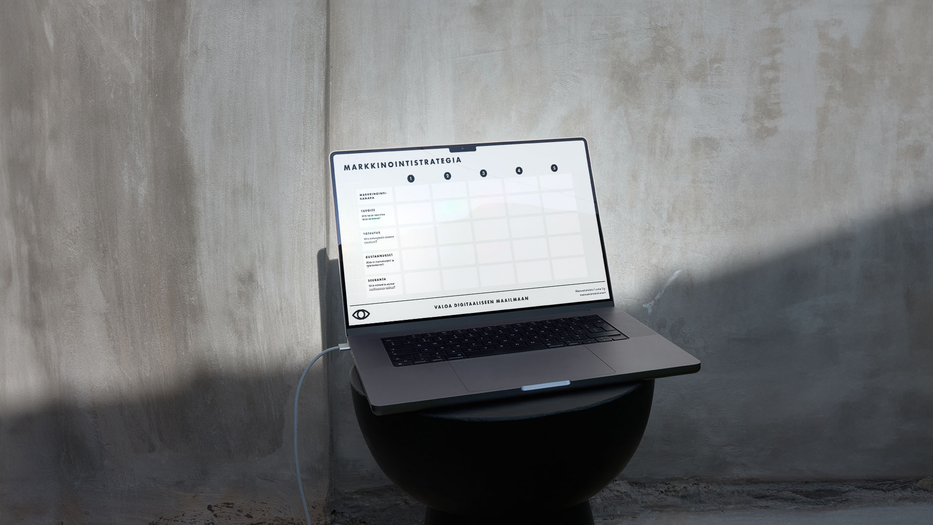Luma Creativen blogiartikkelin pääkuva, jossa on kannettava tietokone asetettuna mustalle alustalle betoniseinää vasten luonnonvalossa. Kuva visualisoi pienen yrityksen markkinoinnin strategista suunnittelua ja selkeää käyttöliittymäsuunnittelua.