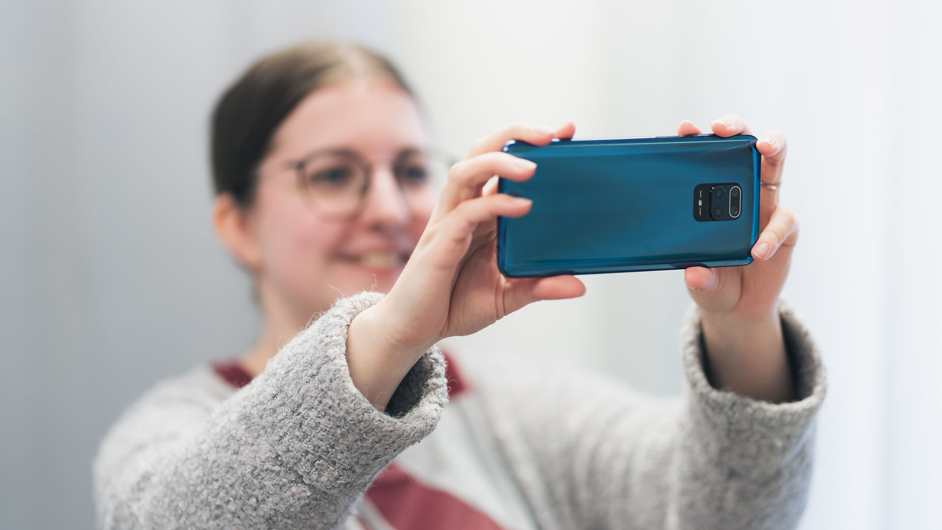 Luma Creativen blogiartikkelin pääkuva, jossa nuori nainen ottaa valokuvaa älypuhelimella.Kuva on otettu pehmeässä valossa ja se visualisoi arjen valokuvausta sekä puhelimen kameran hyödyntämistä markkinoinnissa.