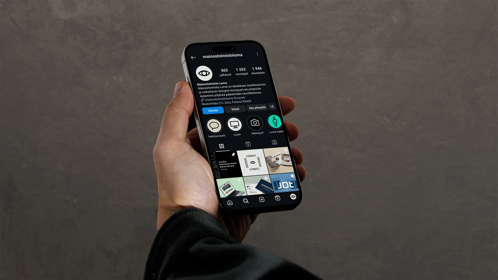 Luma Creativen blogiartikkelin pääkuva, jossa kädessä pidetään älypuhelinta (mobiilinäkymä) harmaata betoniseinää vasten. Kuvitus visualisoi PK-yritysten sosiaalisen median läsnäoloa ja brändinhallintaa vuonna 2025.