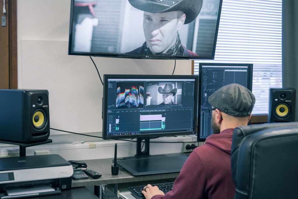 Luma Creativen videotuotantoa esittelevä kuva, jossa editointipöydän äärellä työstetään "Lännen nopein rengasliike" -videota. Kuvassa näkyy ammattimainen editointiympäristö useine näyttöineen, aktiivikaiuttimet sekä videon editointiohjelmiston aikajana.